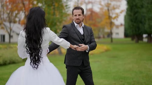 Busty Brunette Bride in White Dress and Her Groom are Walking Together on Street in Autumn Day