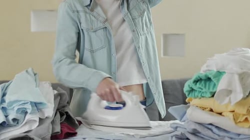 Woman Ironing Clothes at Home on Ironing Board