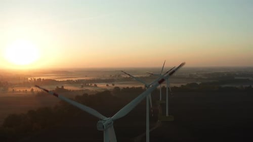 Drone Shot on a Wind Farm Tower in a Field at Sunrise with Fog