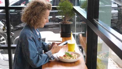 Young Fashionable Woman Using Smartphone On Lunch At Healthy Bistro