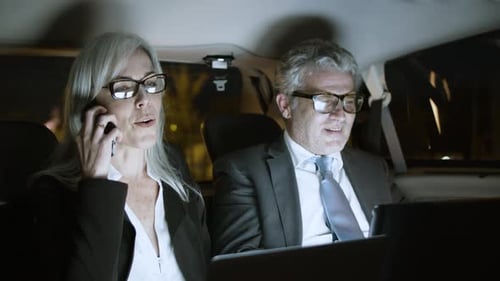 Geschäftsleute, die während der Fahrt im Auto mit Gadgets arbeiten