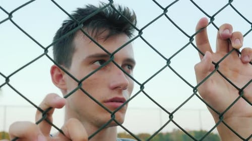 Young Adult Behind a Fence Looking Sad