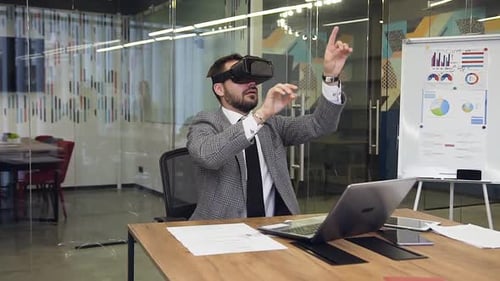 Young Serious Bearded Businessman in Virtual Reality Headset Working in Office Room