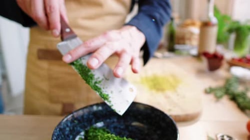 Hands Mincing Herbs in Kitchen with Cleaver