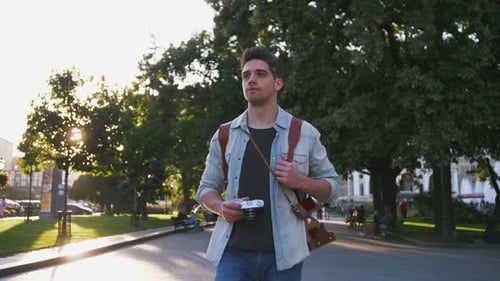 Attractive Young Handsome Man Tourist with Backpack Walking in City Center and Looking Around Slow