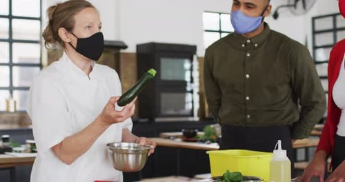 Chef Explains Recipe to Masked Assistants in Kitchen
