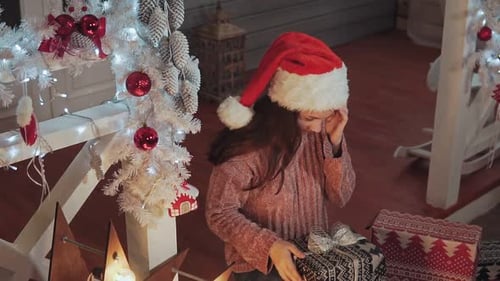 Girl Opening Christmas Present in Decorated Home