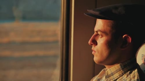 Young Man Gazing Out Window in Golden Light
