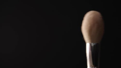 Primer plano de una brocha de maquillaje con polvo facial