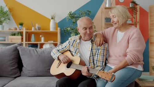 Senior Couple Playing Guitar at Home Together