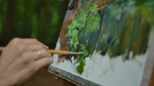 Die Hand eines jungen Mädchens macht ein paar Striche auf den Landschaftszeichnungen im Wald