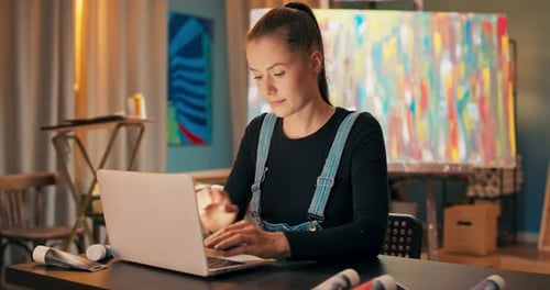 Pretty Experienced Painter Works in a Salon a Painting Studio Sits at Desk in Front