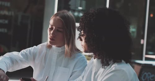 Two women look at laptop and discuss business