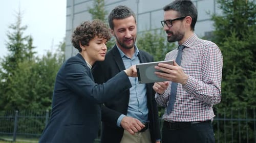 Business Team Discussing Tablet Technology Outdoors