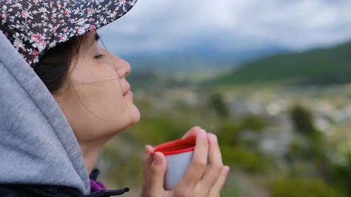 Young Adult Enjoys Drink Amidst Mountain Serenity