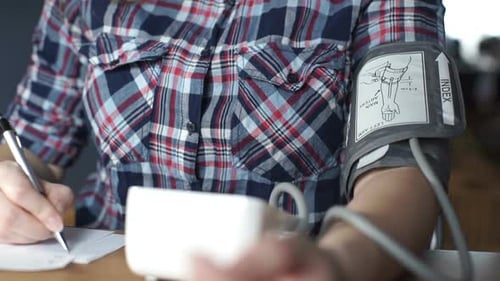 Woman Taking Blood Pressure and Writing