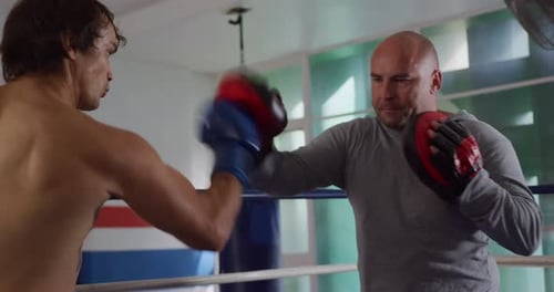 Boxing Trainer Holding Pads for Boxer in Gym