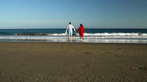 Couple in Love Carefree Running To the Water on the Beach