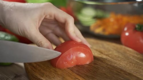 Slicing Fresh Tomato with Knife on Wooden Board