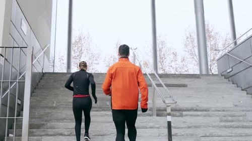 Two athletes training on steps running upstairs