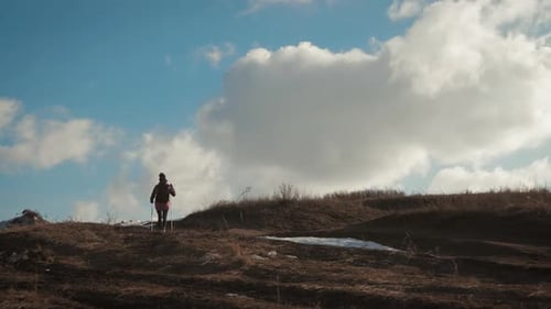 Woman Hiker Ascending a Hill with Hiking Poles