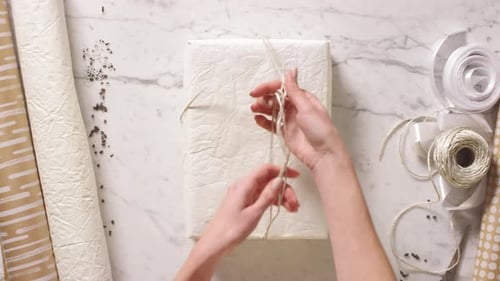 Hands Untying Bow on Birthday Gift with Tablet