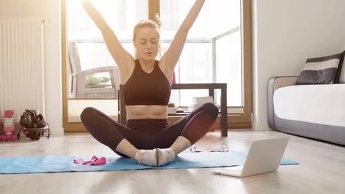 Hermosa mujer joven deportiva en ropa deportiva viendo tutoriales en Vídeo de acondicionamiento físico en línea en una computadora portátil