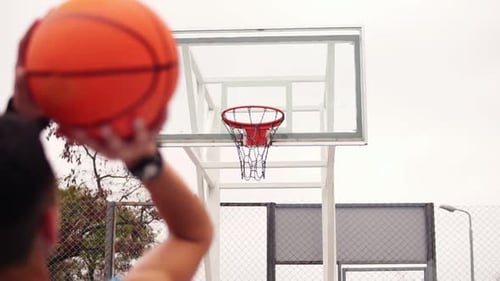 Lanza una canasta de baloncesto, la pelota golpea el ring y vuela por la red