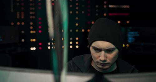 Um jovem hacker cansado com olheiras sob os olhos está usando o computador para organizar