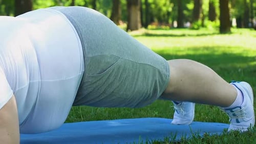 Mann in Übergröße macht Planke auf Matte im Park, versucht, zusätzliches Gewicht zu verlieren, Fettleibigkeit