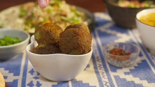 Hand Takes Falafel Bite From Bowl
