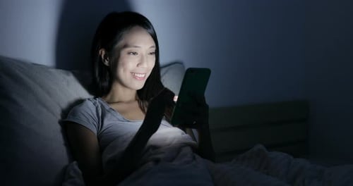 Woman Lies in Bed Using Smartphone at Night