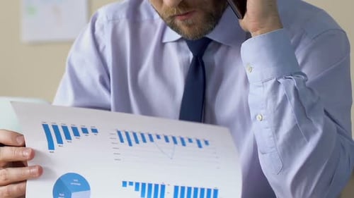 Businessman Talking on Phone and Analyzing Financial Report in Office, Manager