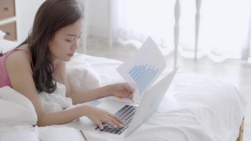 Young Woman Working on Laptop in Bed