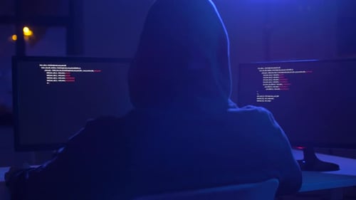 Hooded Hacker at Computer Station in the Dark