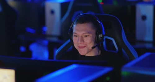 Guy is Sitting at the Computer with Headphones Playing a Computer Game