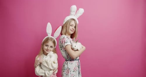 Nette Mädchen mit Hasenohren, die mit dem Kaninchen auf isoliertem Hintergrund spielen