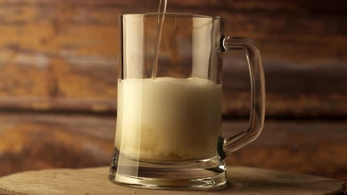 Foamy Beer Being Poured into Glass Mug