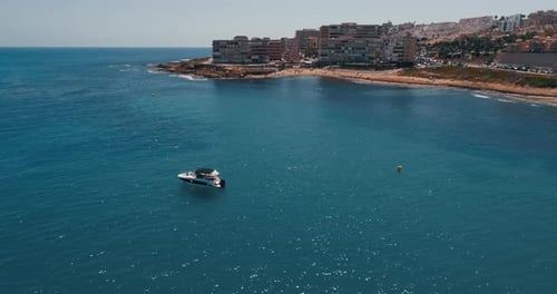 Drone Flying Around Small Motor Boat Parked in Anchor Close to the Beach