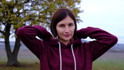 Woman Puts on Hood Outdoors on a Chilly Day