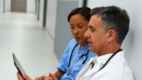 Doctor and Nurse Looking at a Tablet in Hospital