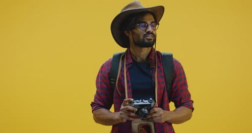 Young Adult Man With Camera on Yellow Background