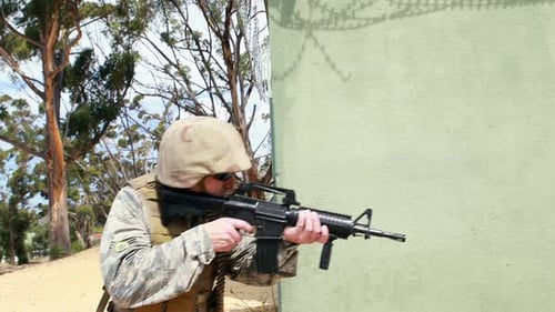 Soldier Walking Beside Building with a Rifle