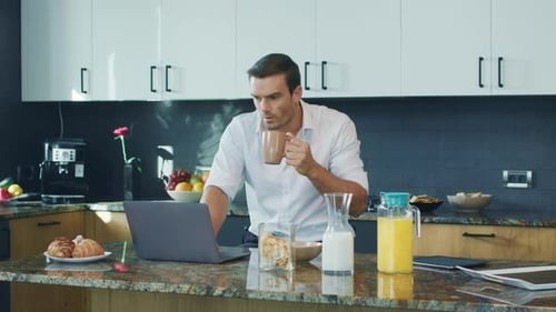 Business Man Watching Video Big Kitchen. Shocked Man Looking at Laptop Computer