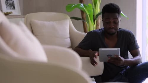 Young Adult Uses Tablet in Living Room
