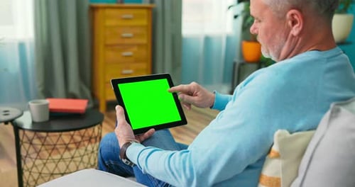Senior Man at Home Uses Green Mockup Screen Tablet