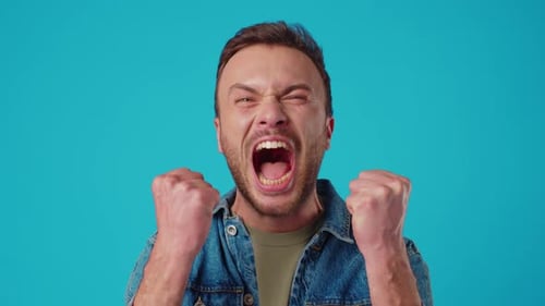 Joven enojado gritando sobre fondo azul