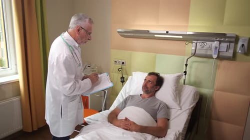 Elderly Doctor Making Notes During Patient Visit