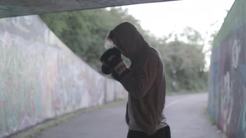 Medium Shot of Young Active Man Boxing In Underpass, Silhouetted By Light - Ungraded
