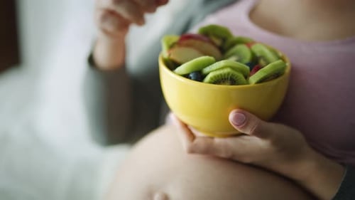 Pregnant Woman Enjoys Bowl of Fruit Salad